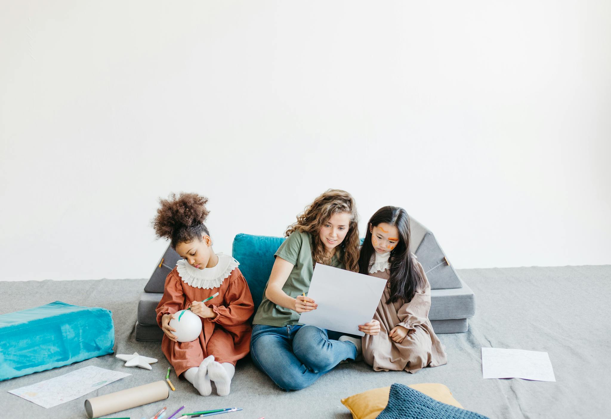 A teacher and children engaging in a creative art session with drawings and crafts.